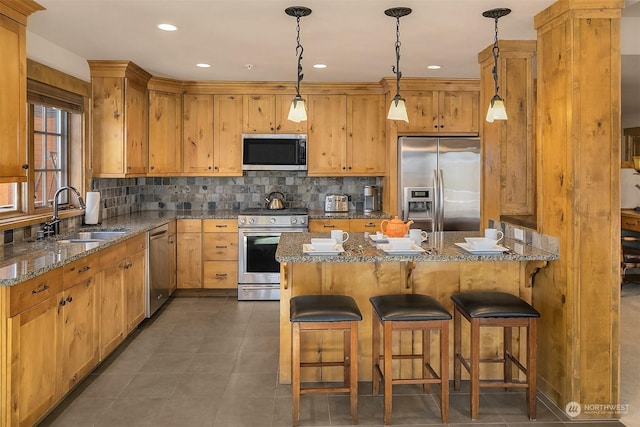 kitchen with stainless steel appliances, dark stone counters, and sink