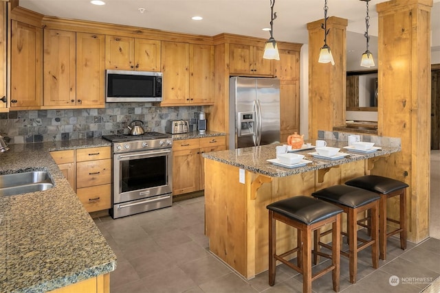 kitchen featuring stainless steel appliances, sink, backsplash, hanging light fixtures, and dark tile patterned floors