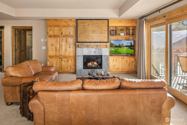 living room featuring a raised ceiling, a tile fireplace, and light carpet