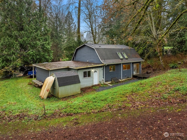 rear view of property with a lawn and a shed