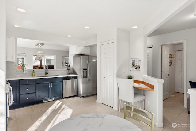 kitchen featuring sink, light tile patterned floors, blue cabinetry, stainless steel appliances, and white cabinets