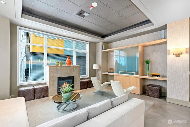 living room with a tray ceiling, a fireplace, and concrete flooring