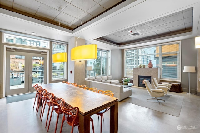 dining space with a premium fireplace, a wealth of natural light, and a tray ceiling