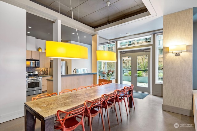 dining area featuring a raised ceiling, a wealth of natural light, french doors, and sink