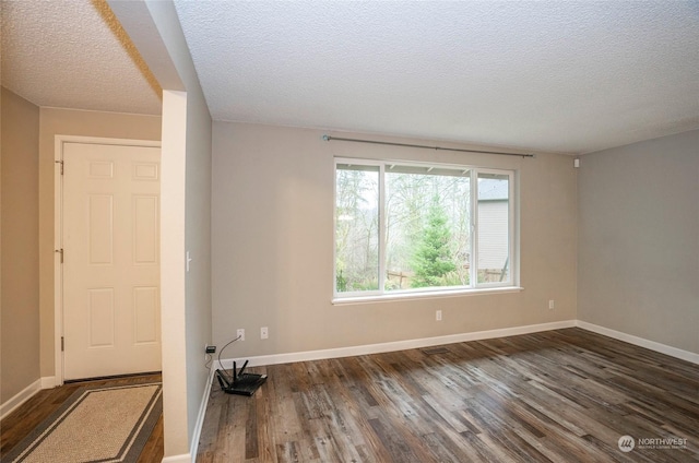 spare room featuring dark wood-type flooring and a textured ceiling