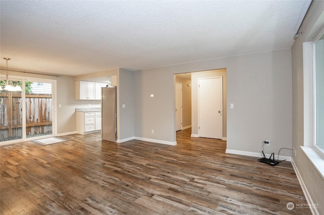 unfurnished living room with dark wood-type flooring and a textured ceiling