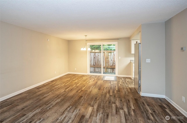 unfurnished room featuring an inviting chandelier, dark hardwood / wood-style floors, and a textured ceiling