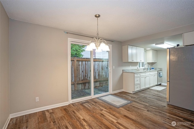 kitchen featuring stainless steel appliances, dark hardwood / wood-style floors, hanging light fixtures, and white cabinets