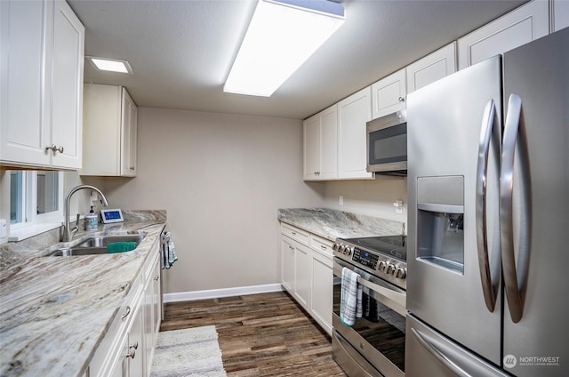 kitchen with white cabinetry, stainless steel appliances, sink, and light stone counters