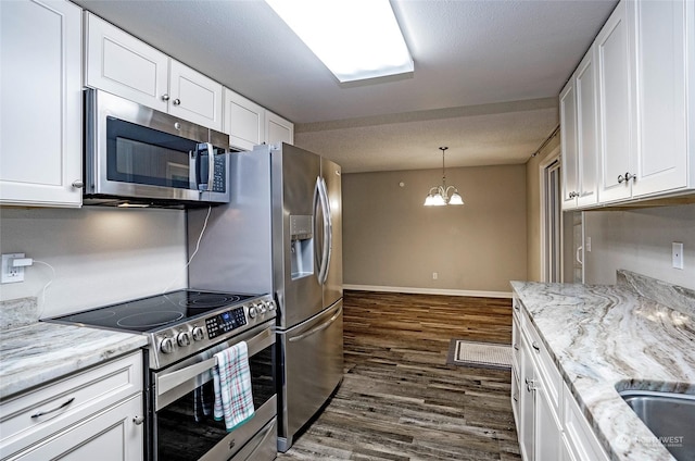 kitchen with white cabinets, a notable chandelier, light stone counters, stainless steel appliances, and dark wood-type flooring