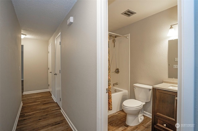 full bathroom with wood-type flooring, bathtub / shower combination, vanity, toilet, and a textured ceiling