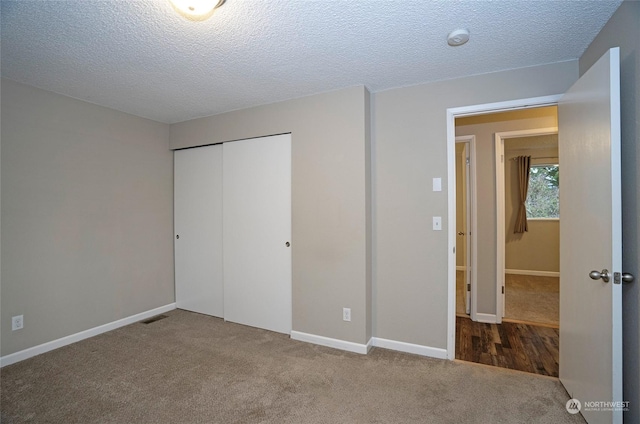 unfurnished bedroom with carpet, a textured ceiling, and a closet