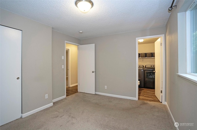 unfurnished bedroom featuring connected bathroom, light colored carpet, a textured ceiling, and independent washer and dryer