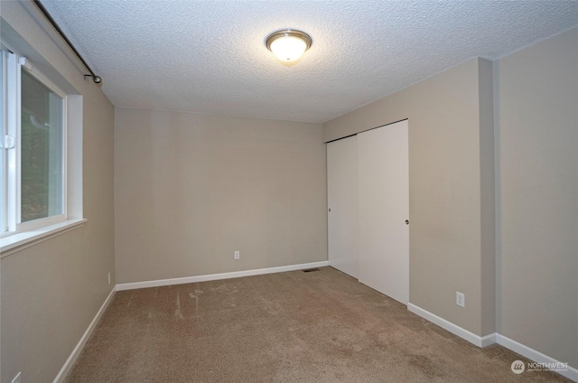 carpeted empty room featuring a textured ceiling