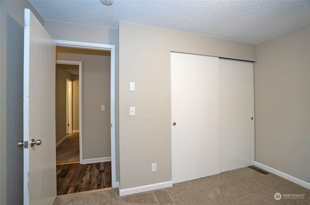 unfurnished bedroom with carpet, a closet, and a textured ceiling