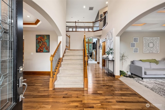 foyer entrance featuring dark hardwood / wood-style floors, crown molding, and a high ceiling