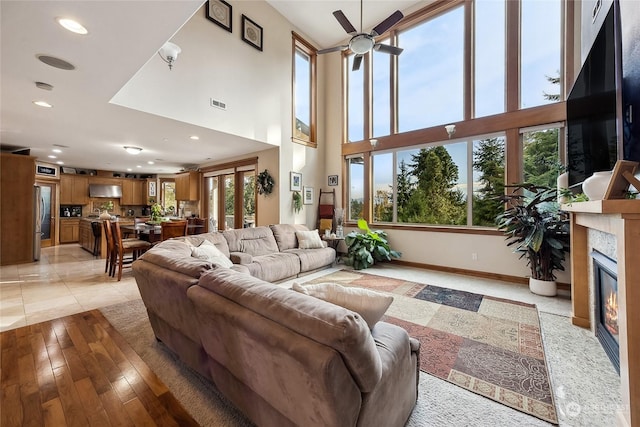 living room with a high ceiling, light hardwood / wood-style flooring, and ceiling fan