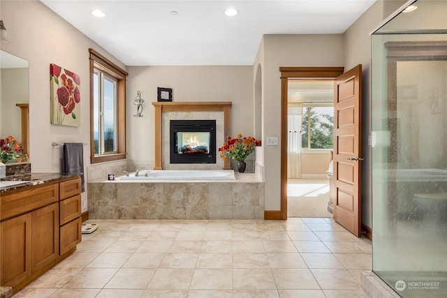 bathroom with tile patterned floors, vanity, a multi sided fireplace, and shower with separate bathtub