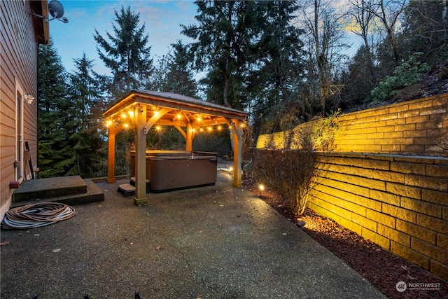 patio terrace at dusk with a gazebo and a hot tub