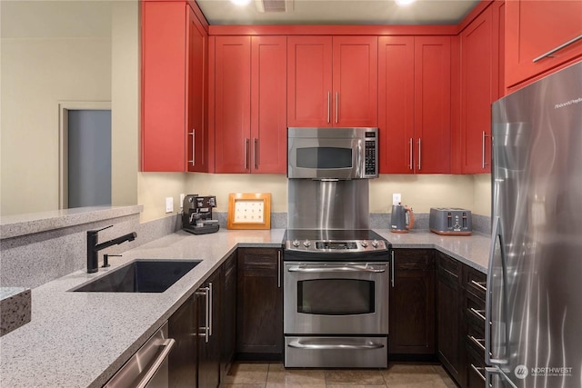 kitchen featuring light stone counters, sink, and appliances with stainless steel finishes