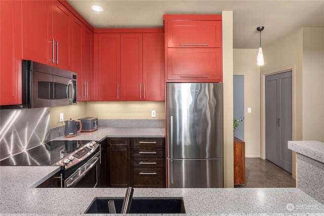 kitchen with light stone counters, sink, pendant lighting, and appliances with stainless steel finishes