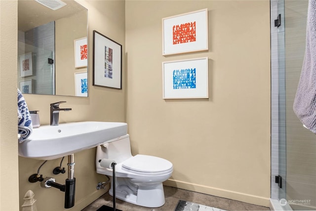 bathroom featuring toilet, tile patterned flooring, a shower with shower door, and sink