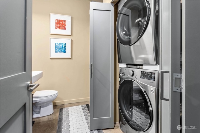 clothes washing area featuring light tile patterned floors and stacked washer and clothes dryer