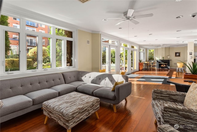 living room featuring ceiling fan, wood-type flooring, crown molding, and a wealth of natural light