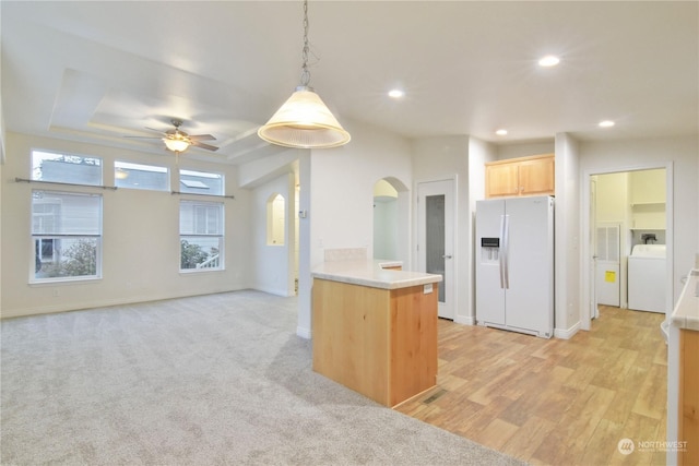 kitchen with kitchen peninsula, a raised ceiling, white refrigerator with ice dispenser, light brown cabinets, and washer / clothes dryer