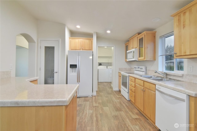 kitchen featuring lofted ceiling, white appliances, washing machine and dryer, light wood-type flooring, and light brown cabinetry