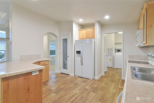 kitchen with light brown cabinets, white appliances, sink, light hardwood / wood-style floors, and washer / dryer