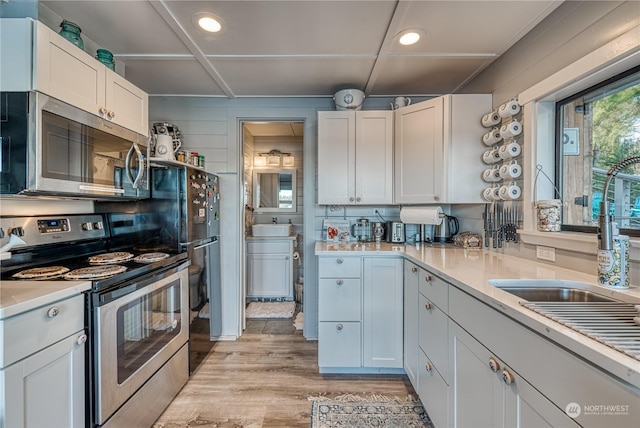 kitchen featuring stainless steel appliances, white cabinetry, and light hardwood / wood-style floors