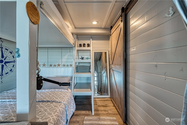 interior space with built in shelves, hardwood / wood-style floors, a barn door, and wooden walls