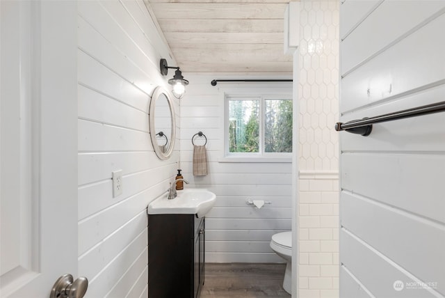 bathroom featuring wood ceiling, hardwood / wood-style floors, toilet, vanity, and wood walls