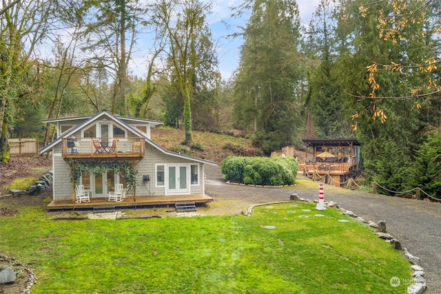 rear view of house featuring a wooden deck, a yard, and french doors