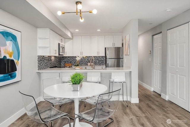 kitchen featuring appliances with stainless steel finishes, white cabinets, backsplash, and kitchen peninsula