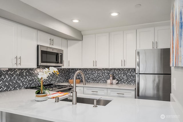 kitchen featuring white cabinets, appliances with stainless steel finishes, backsplash, and sink