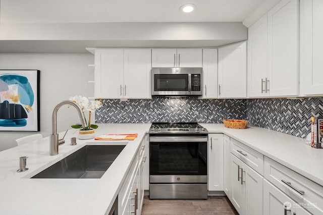 kitchen with white cabinets, appliances with stainless steel finishes, tasteful backsplash, and sink