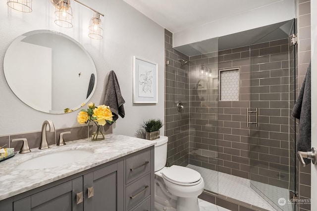 bathroom with toilet, an enclosed shower, and vanity