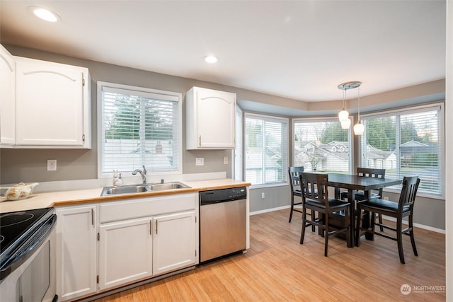 kitchen with white cabinetry, sink, light hardwood / wood-style floors, decorative light fixtures, and appliances with stainless steel finishes