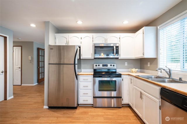 kitchen with sink, white cabinets, stainless steel appliances, and light hardwood / wood-style floors