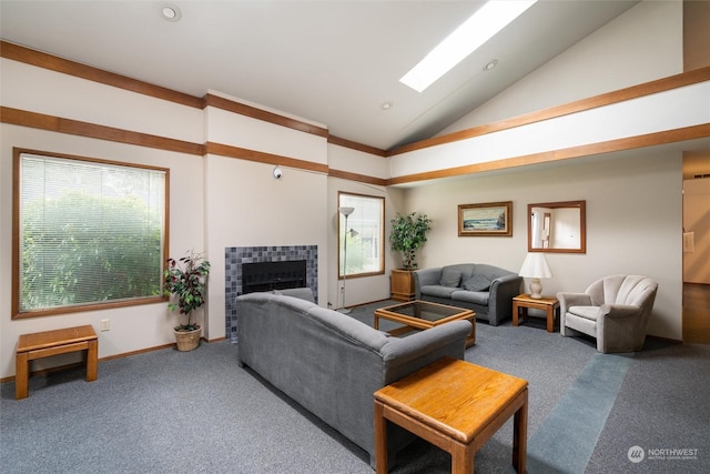 living room with carpet, vaulted ceiling with skylight, a wealth of natural light, and a tiled fireplace