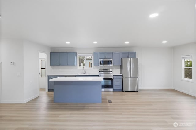 kitchen featuring sink, a kitchen island, stainless steel appliances, and light hardwood / wood-style floors