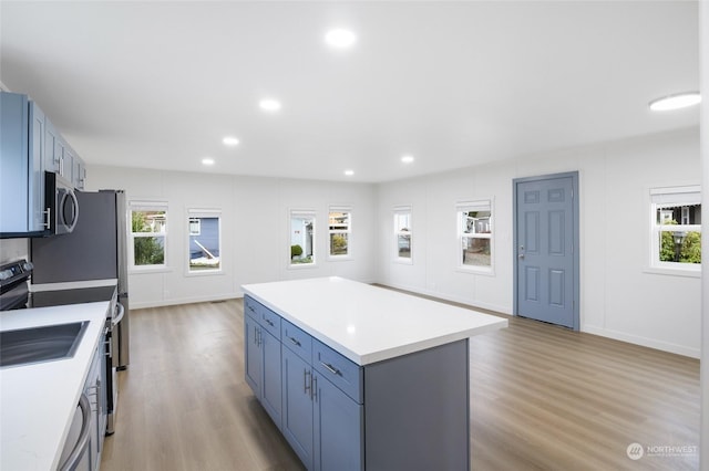 kitchen with a kitchen island, light wood-type flooring, and range with electric stovetop