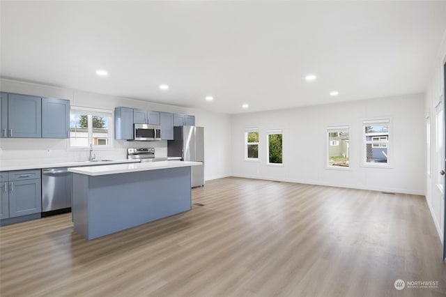 kitchen featuring sink, a kitchen island, stainless steel appliances, and light hardwood / wood-style floors