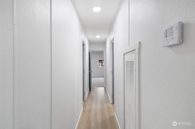 corridor with light hardwood / wood-style floors and crown molding