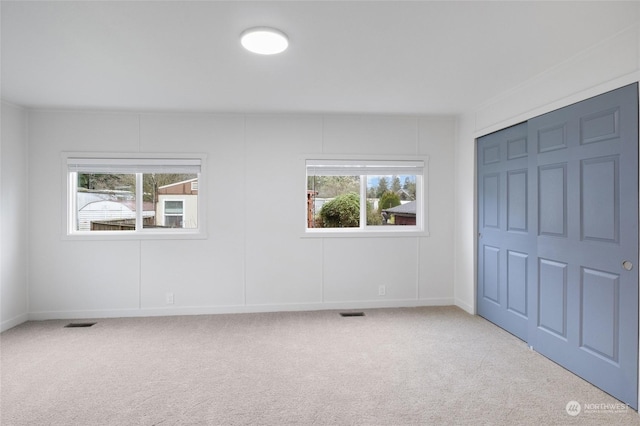 unfurnished bedroom with a closet and light colored carpet