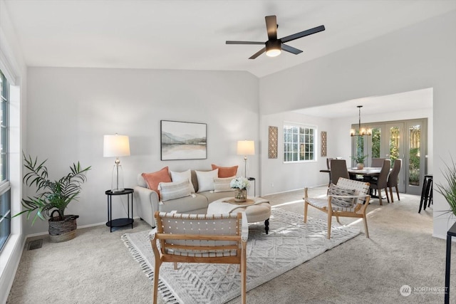 living room featuring ceiling fan with notable chandelier, light colored carpet, and vaulted ceiling