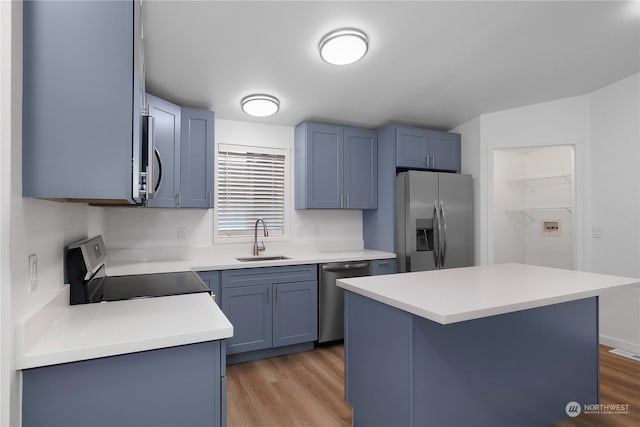 kitchen featuring blue cabinets, sink, a kitchen island, stainless steel appliances, and light hardwood / wood-style floors