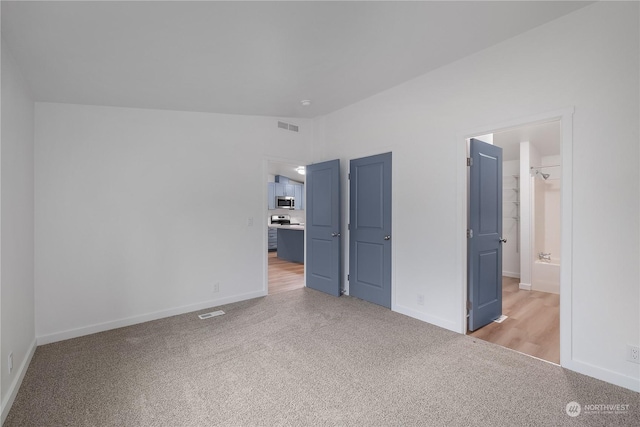 unfurnished bedroom featuring connected bathroom and light carpet